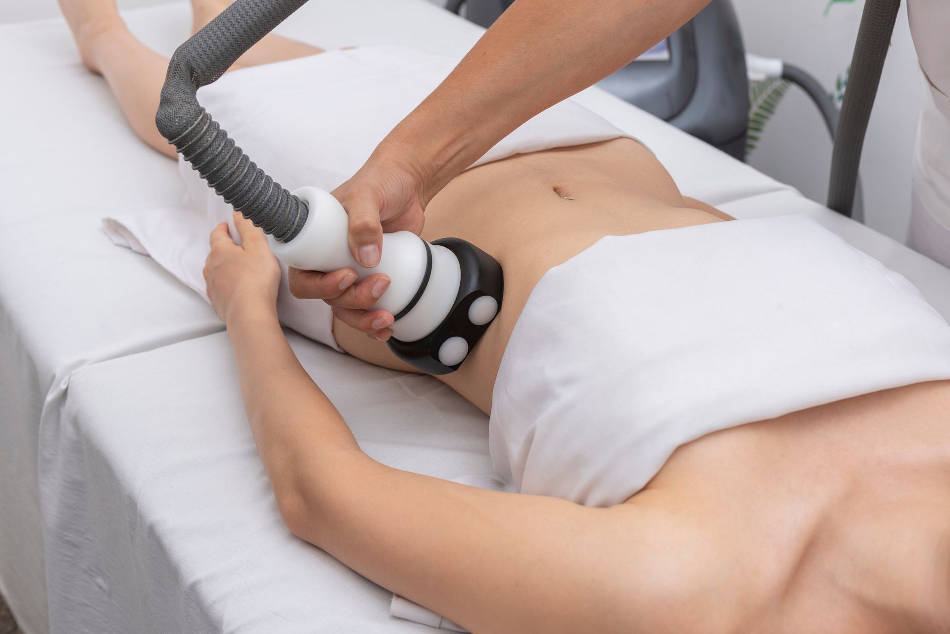 A woman is getting a cavitation treatment on her stomach.