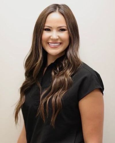 Woman smiling, wearing black shirt, with long brown hair, indoors.