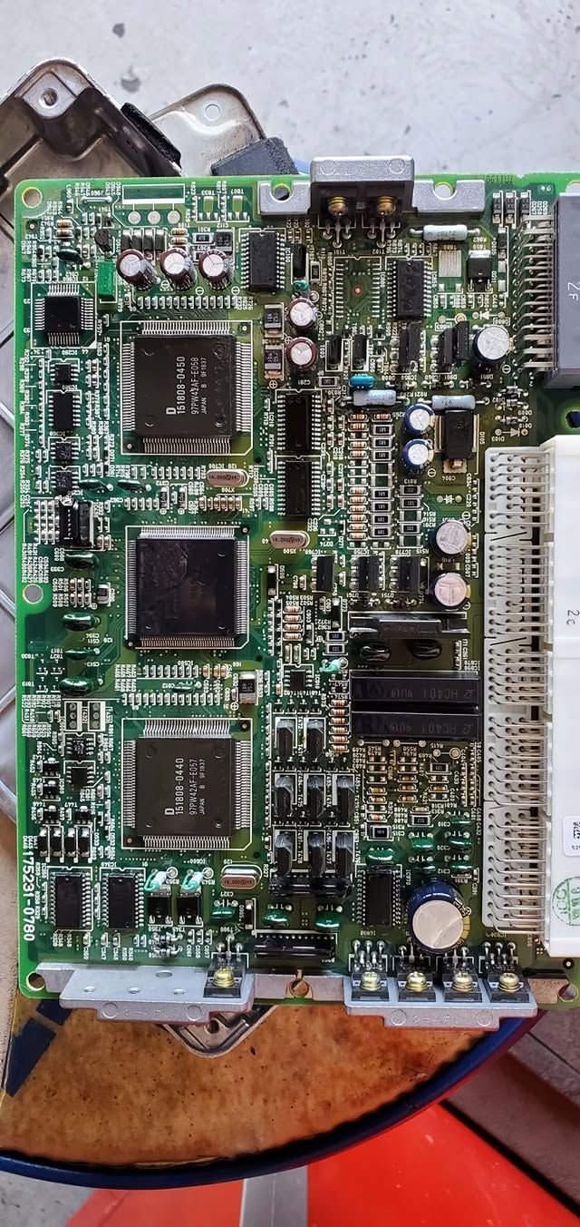 Green printed circuit board with chips and connectors on a work surface