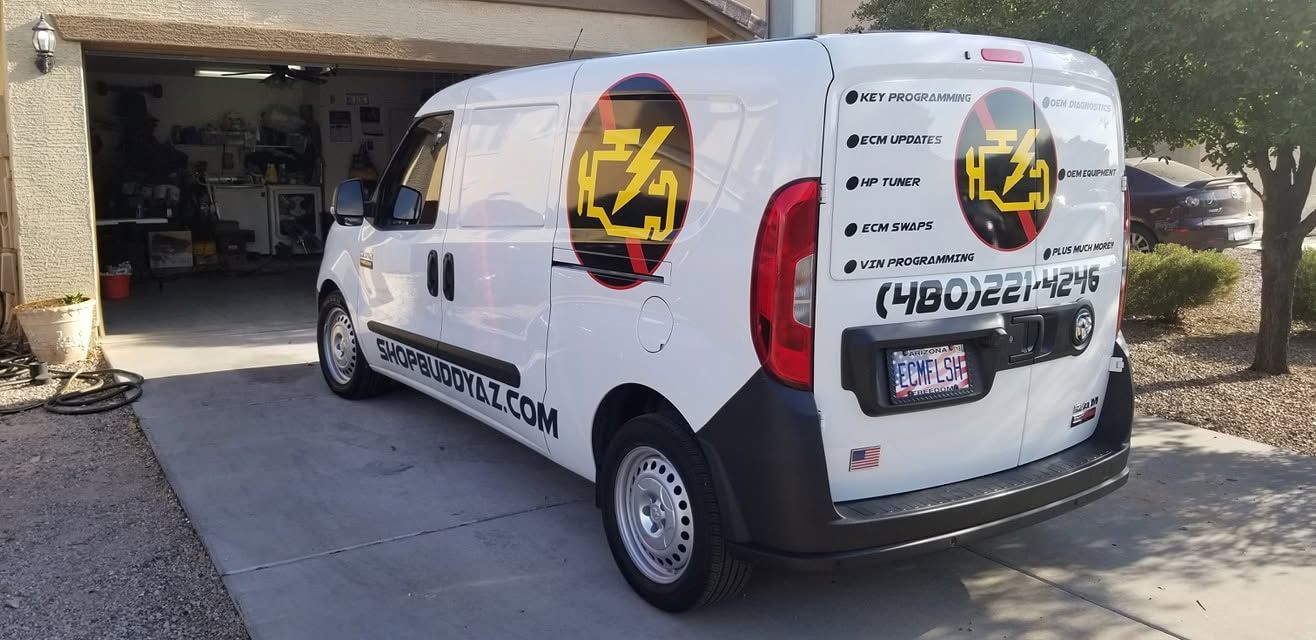 White service van with black-and-yellow logos parked in a driveway outside a garage