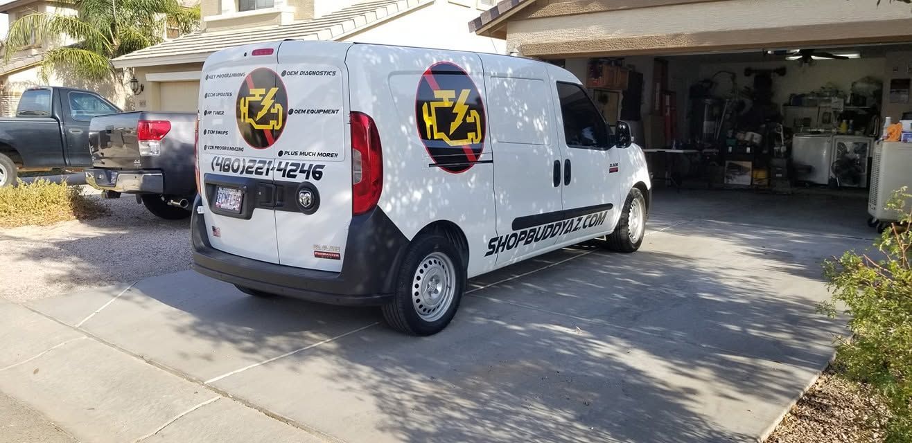 White service van with company logos parked in a driveway beside a garage.