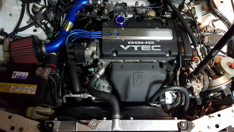 Car engine bay with a black DOHC VTEC cover and blue intake piping