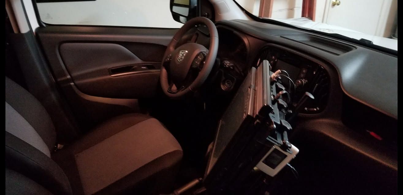Car interior with steering wheel, dashboard controls, and a mounted device on the center console.