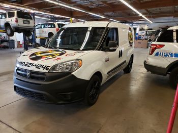 White commercial van in an indoor parking garage, parked beside other vehicles.