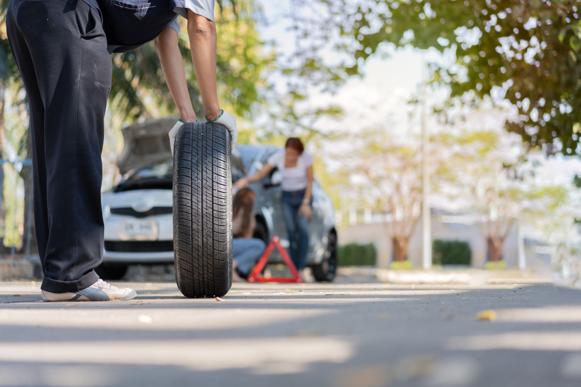 A man is changing a tire on the side of the road.