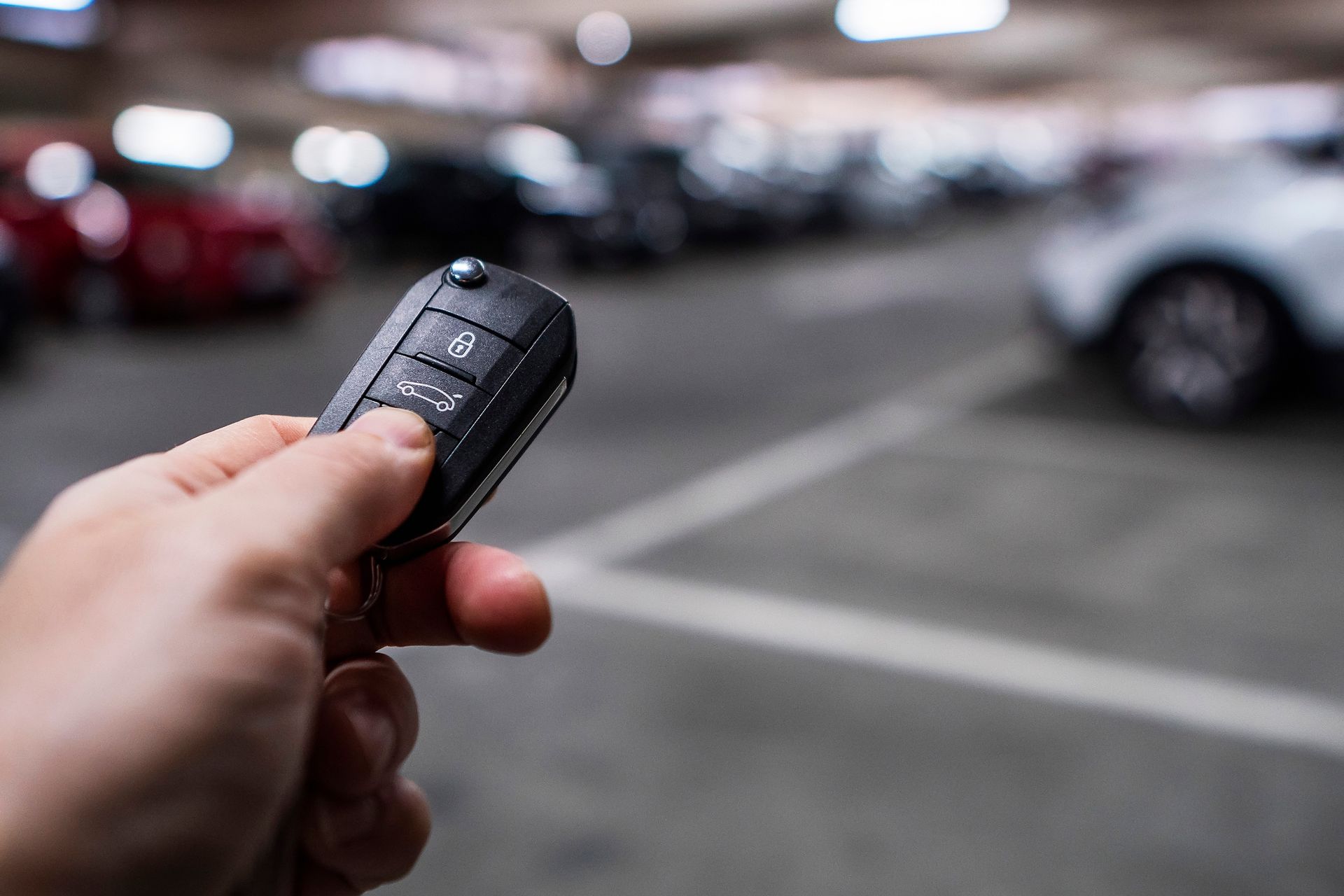 A person is holding a car key in a parking garage.