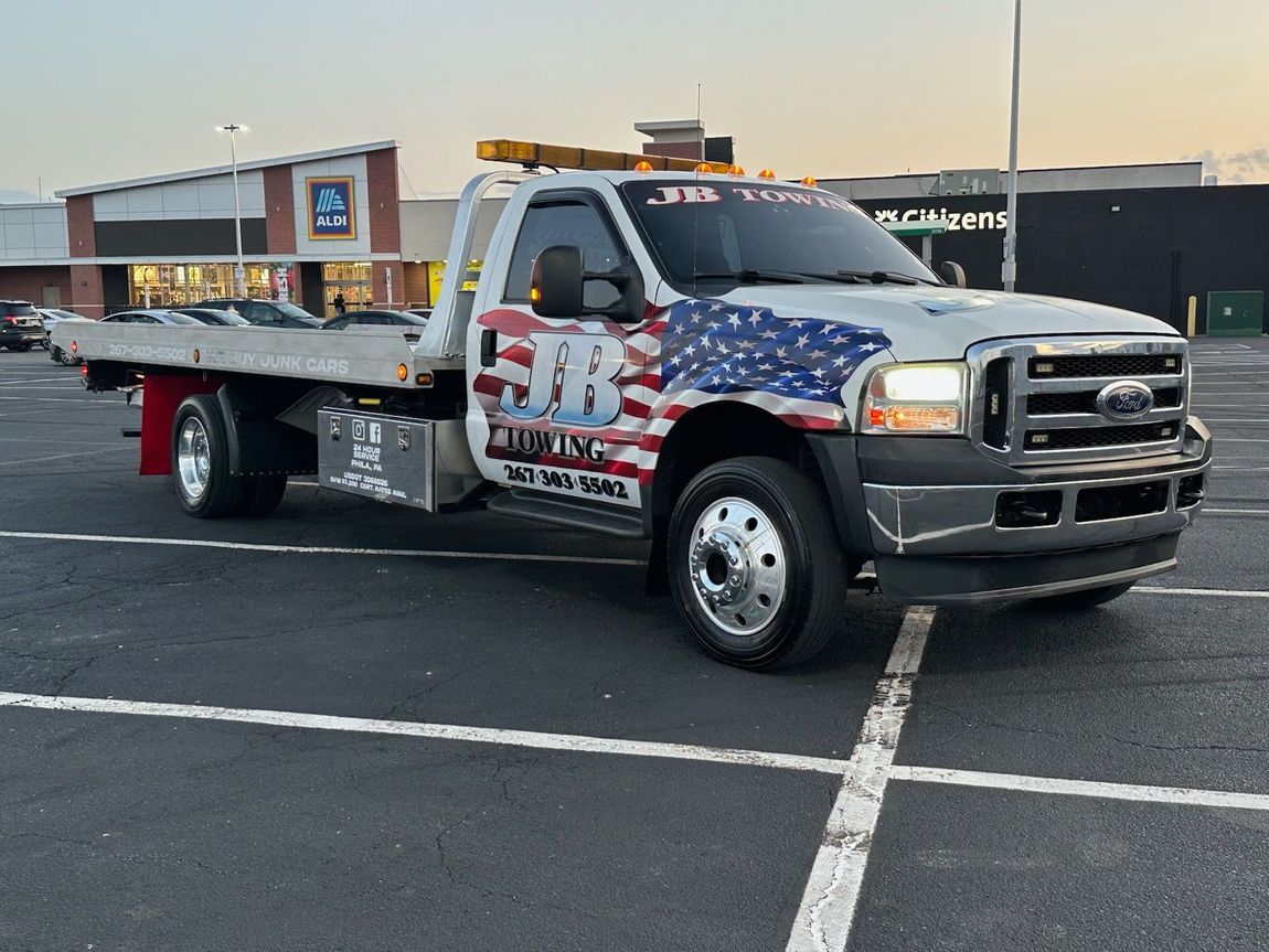 A tow truck is parked in a parking lot in front of a store.