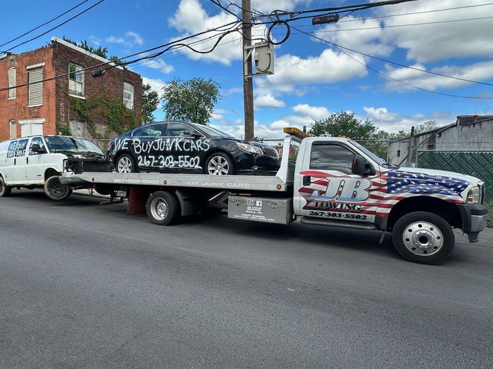 A tow truck is carrying a car on the back of it.