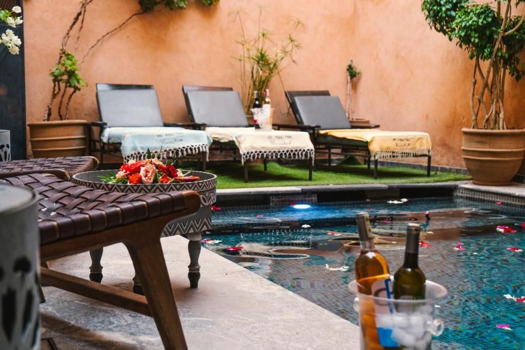 A bottle of wine is in a bucket next to a swimming pool.