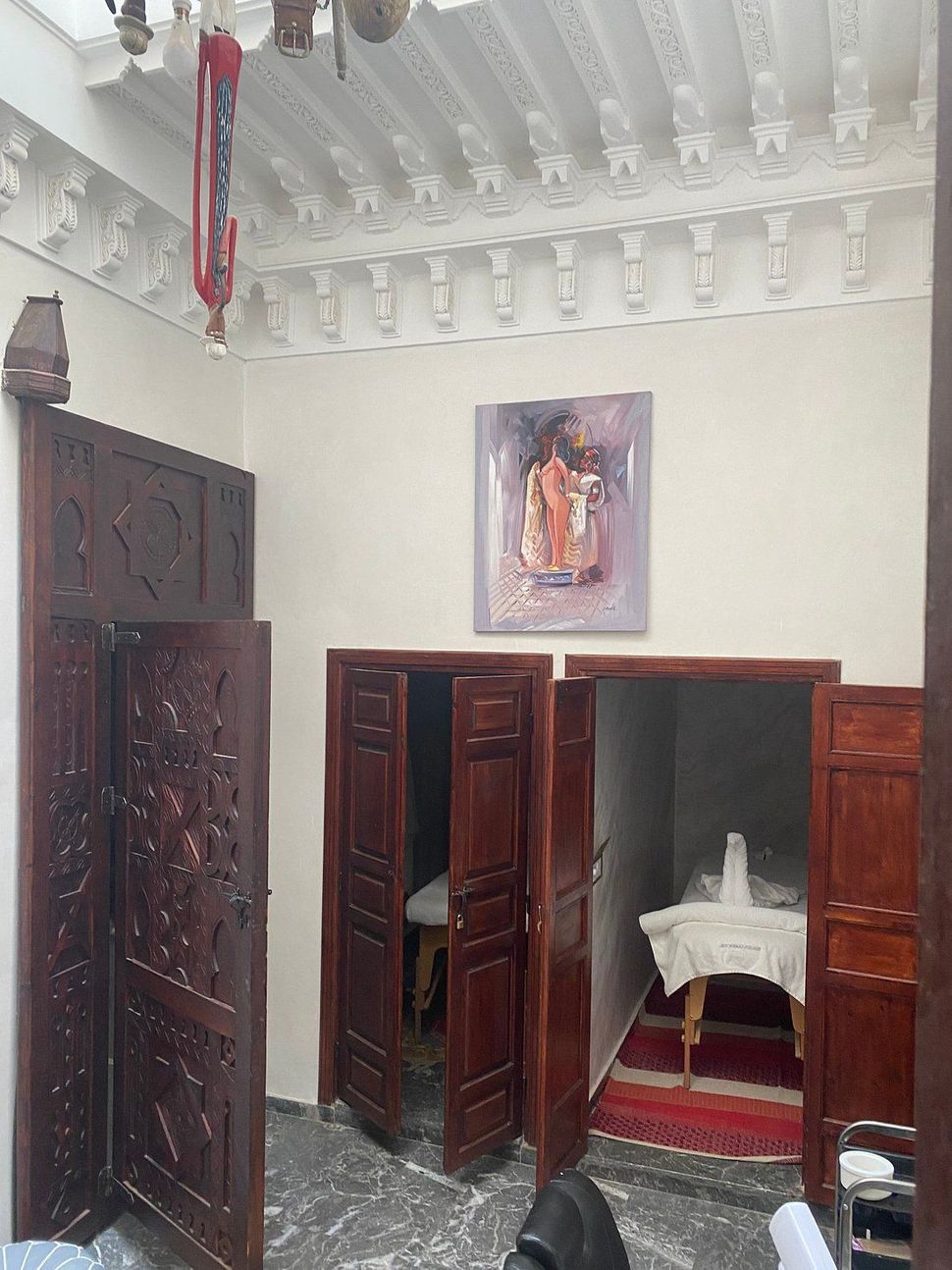 Room with multiple wooden doorways, white ceiling, painting on wall.