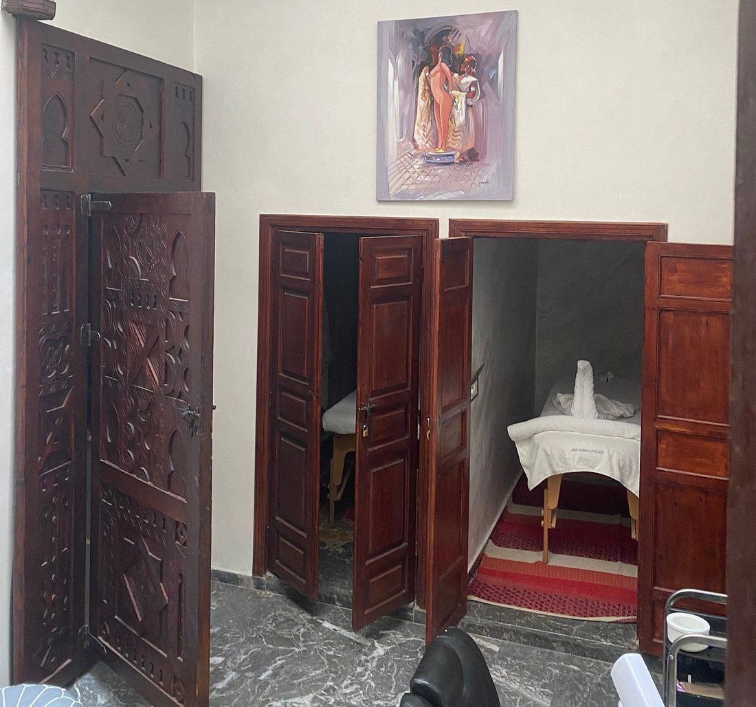 Wooden doors leading to small rooms; one has a table with a white cloth, another a chair. A painting hangs on the wall.
