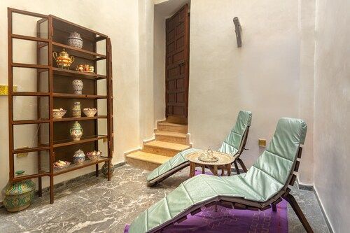 Relaxation area: wooden shelves with pottery, two chaise lounges with green cushions, and a door.