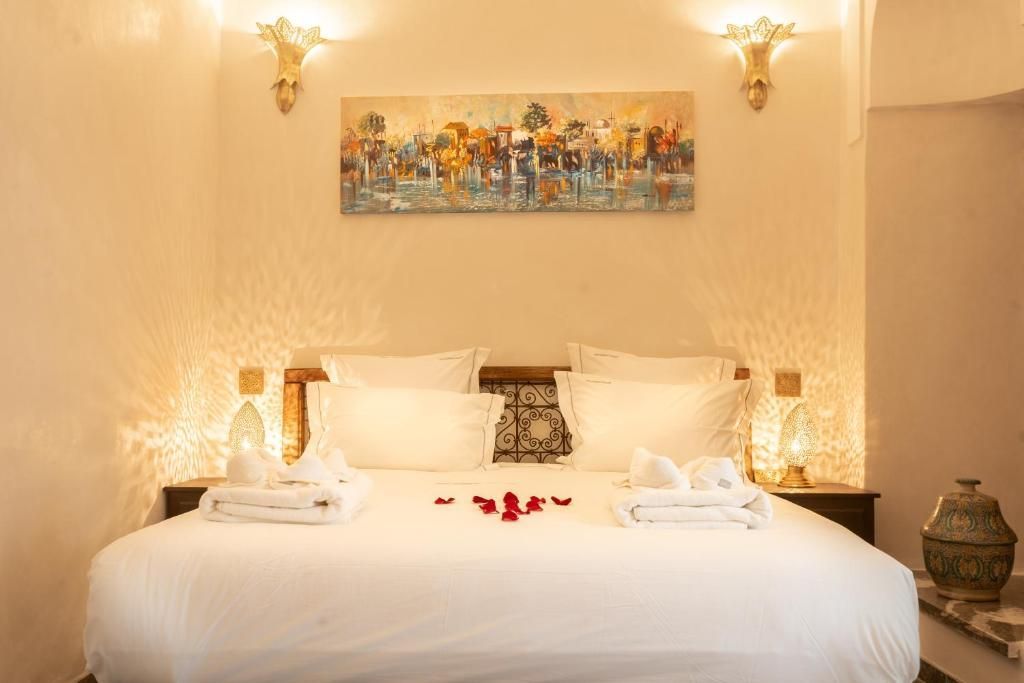 Bedroom with large white bed, artwork, and decorative lighting.