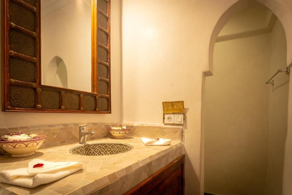 Bathroom with ornate mirror, marble countertop, and arched doorway.