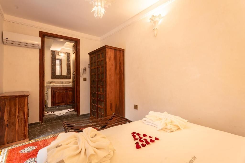 Bedroom with wooden furniture, bed with rose petals, doorway to a bathroom.