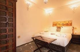 Bedroom with bed, wooden cabinet, and bench. Cream walls, soft lighting, and ornate accents.