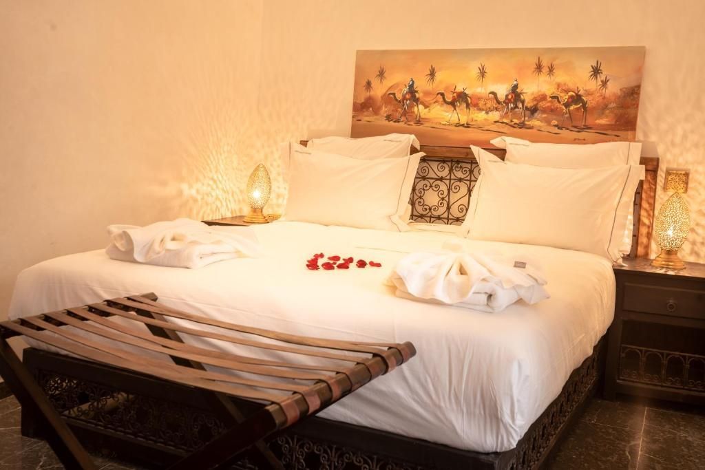 Bedroom with bed, footstool, bedside tables, and desert-themed artwork.