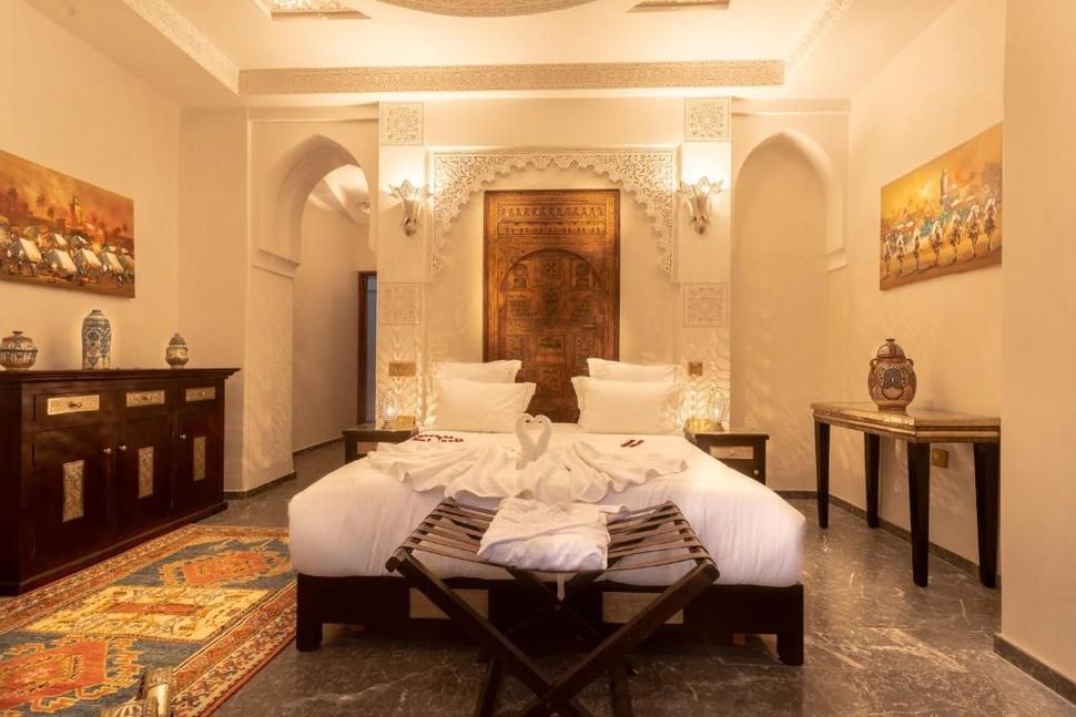 Luxurious bedroom with ornate headboard, arched doorways, decorative art and a plush rug.