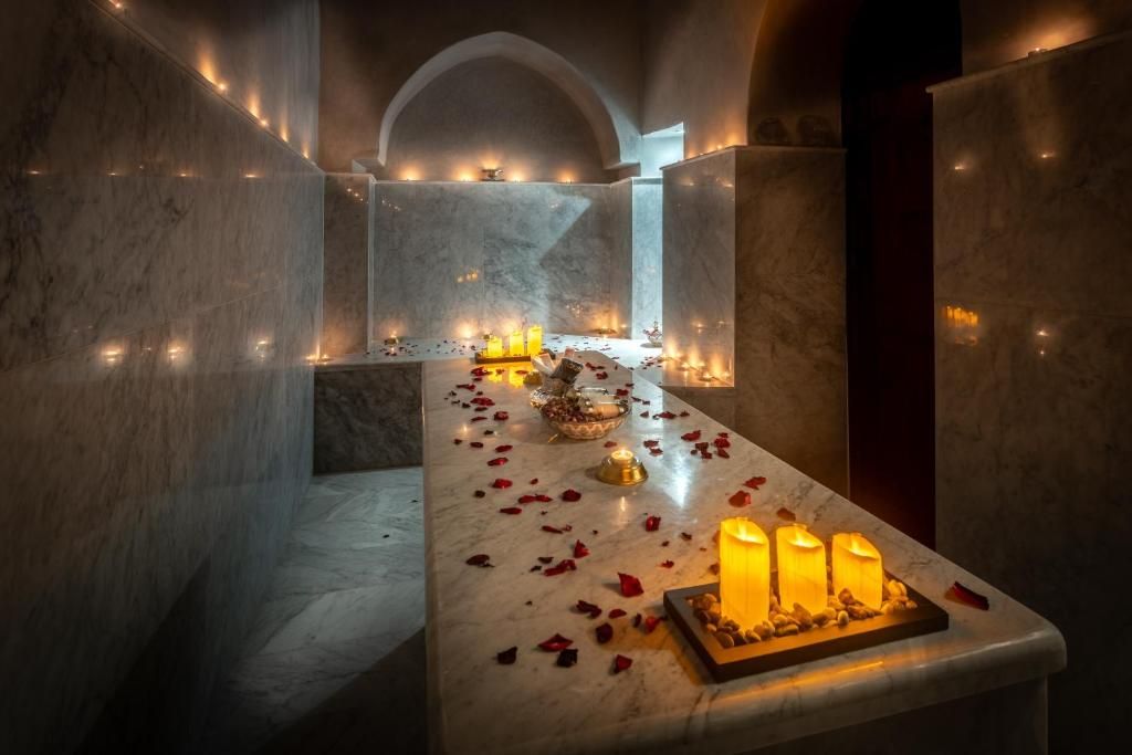 Candlelit spa treatment room with marble surfaces and rose petals.