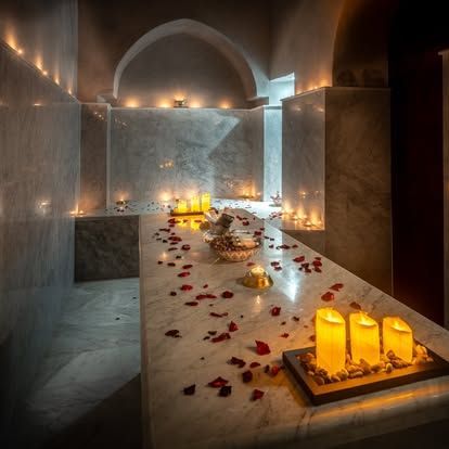 Spa treatment room, marble table with rose petals, lit candles.