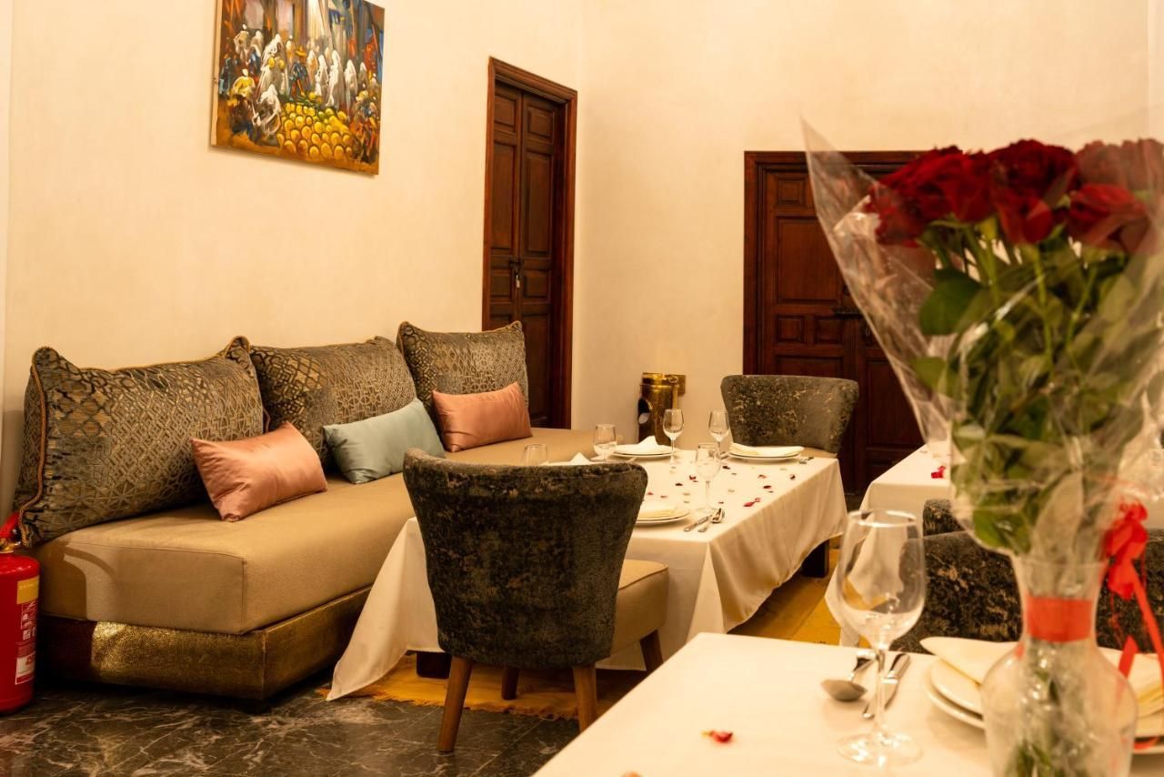 A living room with a couch , chairs , a table and a vase of flowers.