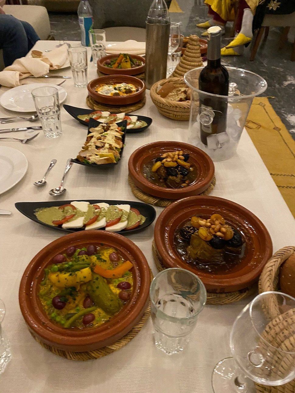 Table set with various Moroccan dishes, including tagines, salads, bread, and wine.