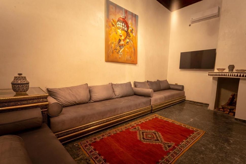 Living room with long sofa, red rug, art, TV, and decorative items.