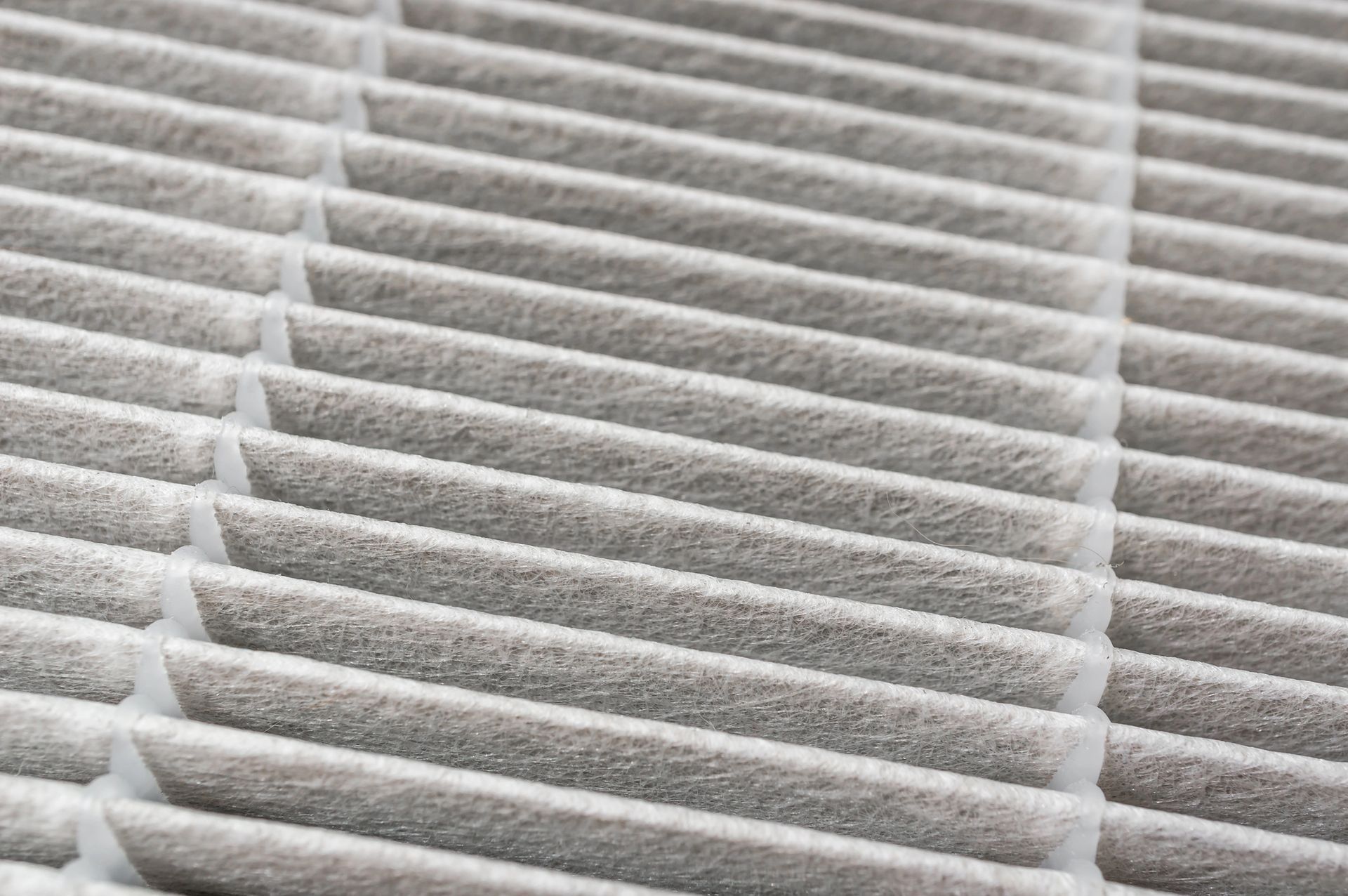 Close-up view of a dirty air filter with multiple angled, pleated layers, coated in gray dust.