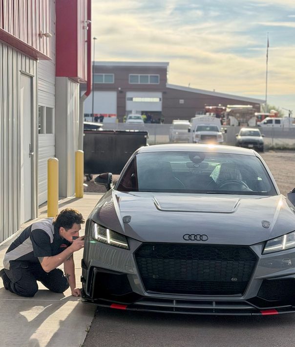 Gray Audi A7 sedan with hood open on a red car lift inside a garage. | Peak European