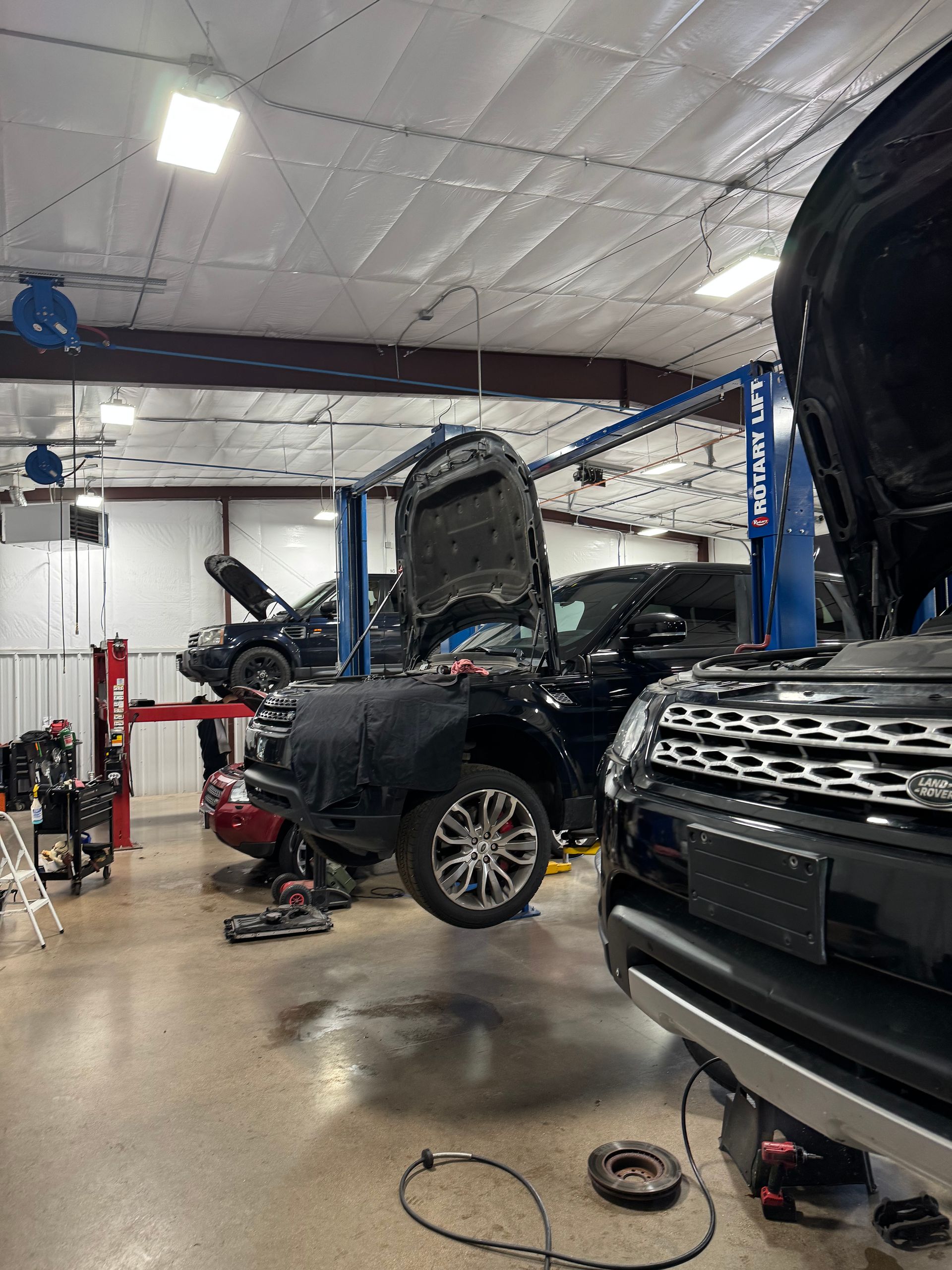 Cars in a garage being repaired with their hoods open | Peak European