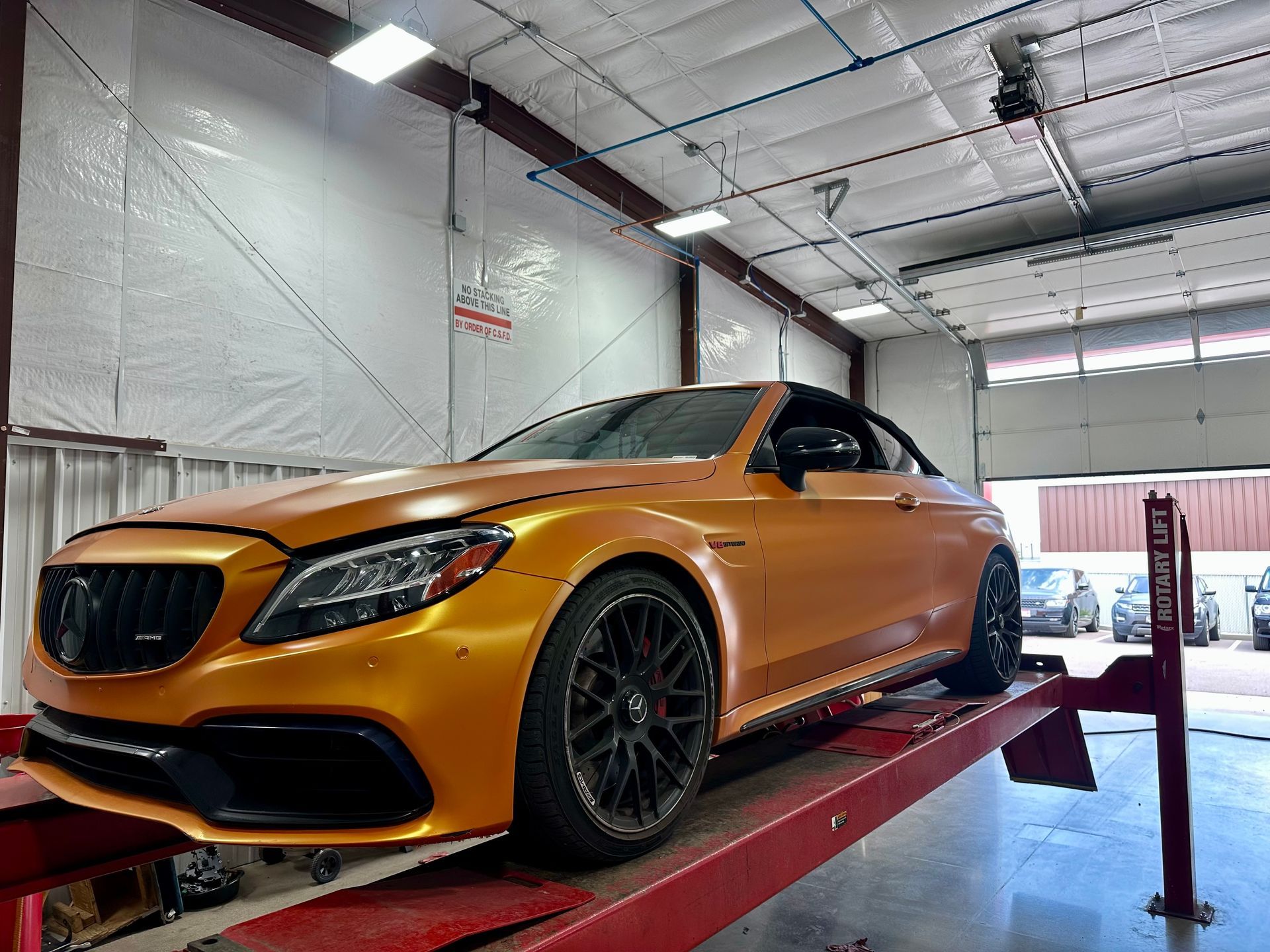 Orange sports sedan on a lift in an auto shop garage