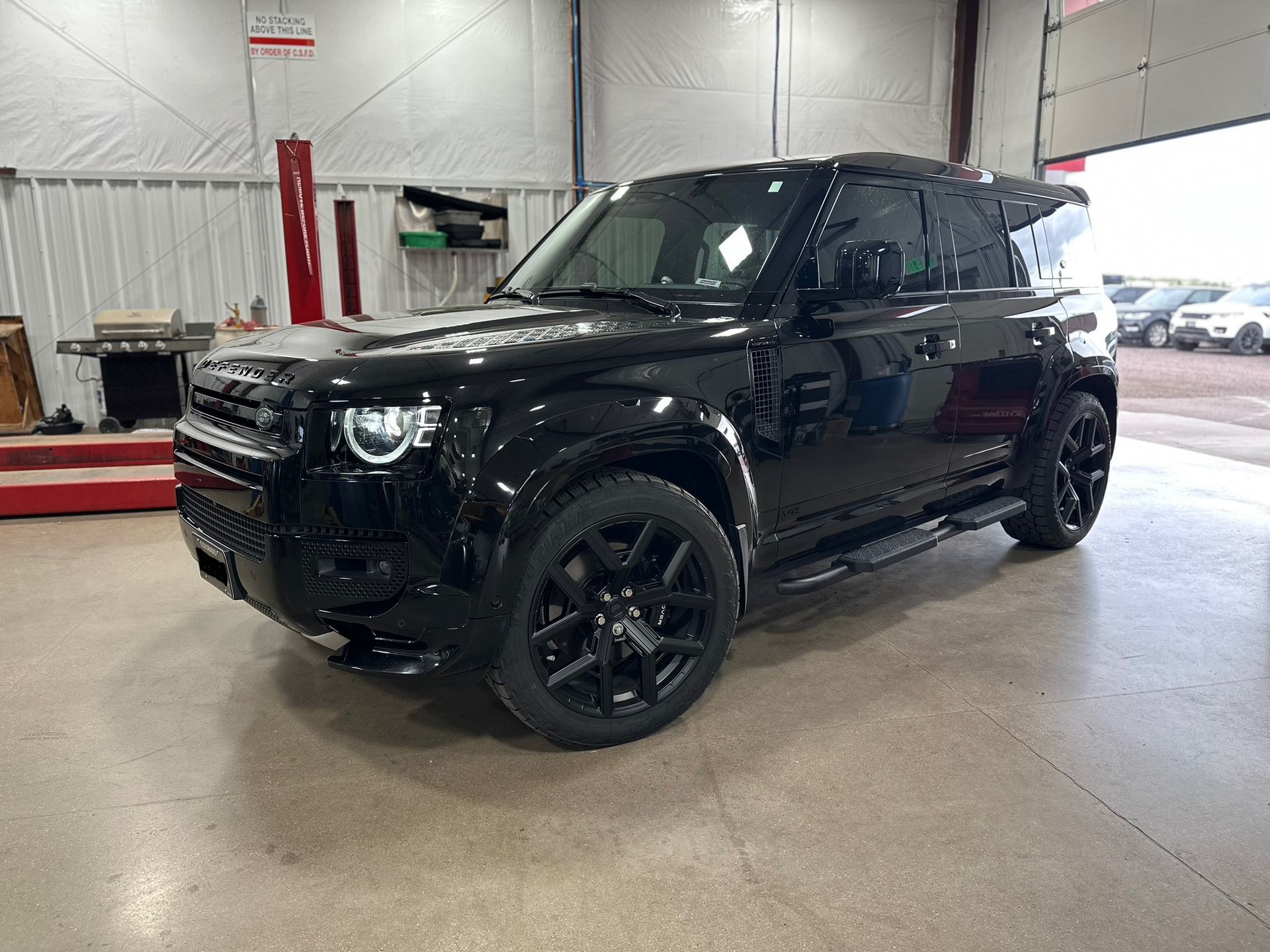 Black SUV parked inside an auto service garage, shown from the front-left side.