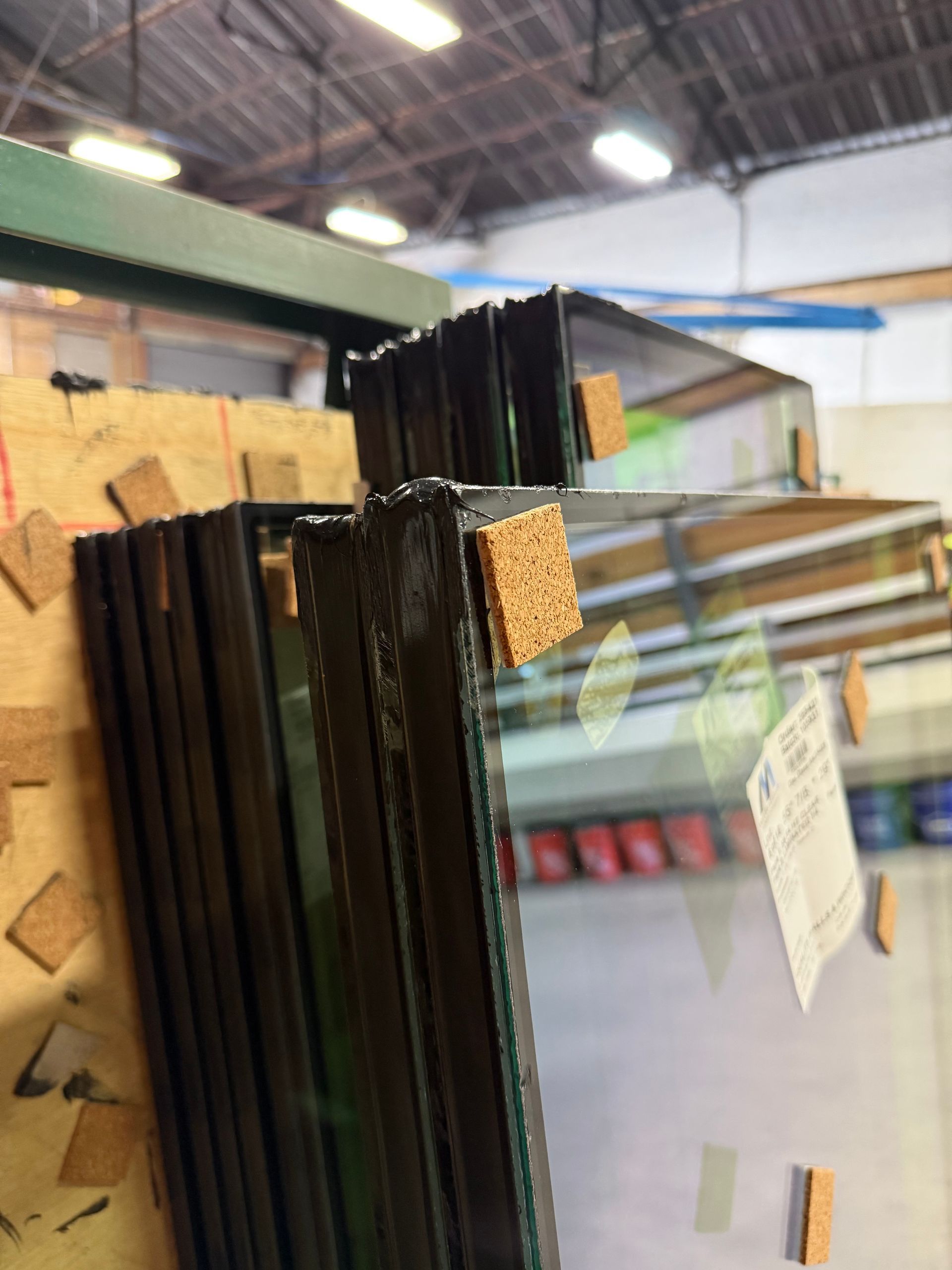 Stack of glass panels with cork spacers in a warehouse setting.