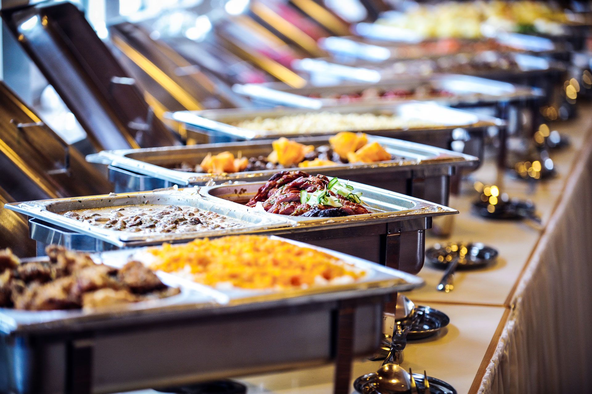 Buffet table with several silver chafing dishes filled with food.