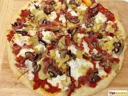 Pizza with mushrooms, artichokes, and red sauce on a wooden surface.