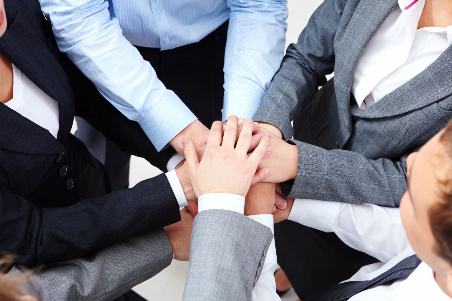 A group of people are putting their hands together