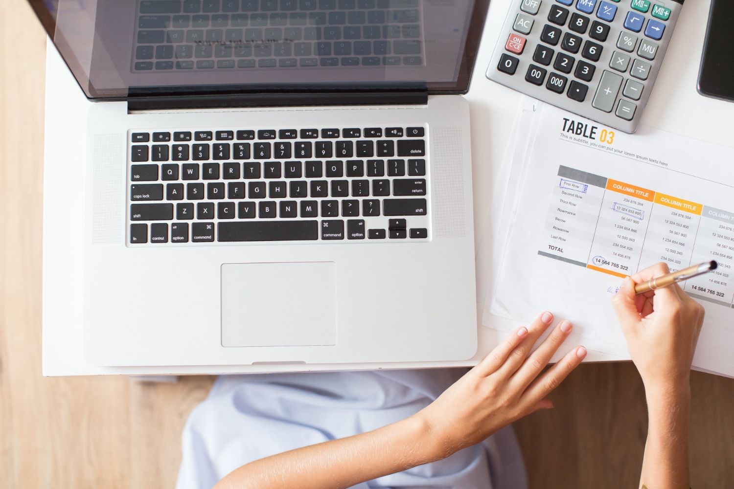 A person is sitting at a desk with a laptop and a calculator.