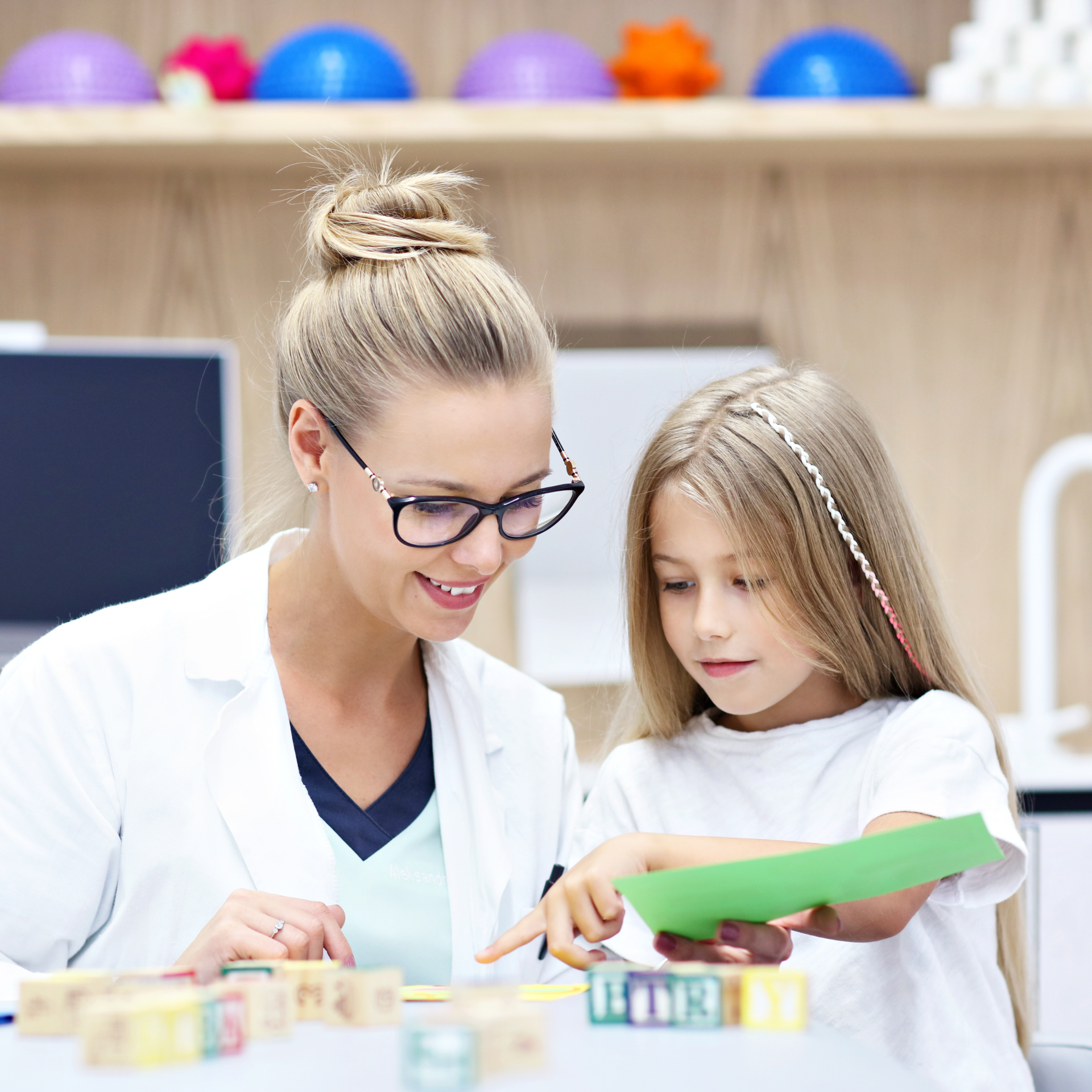a woman and a little girl are playing with blocks .