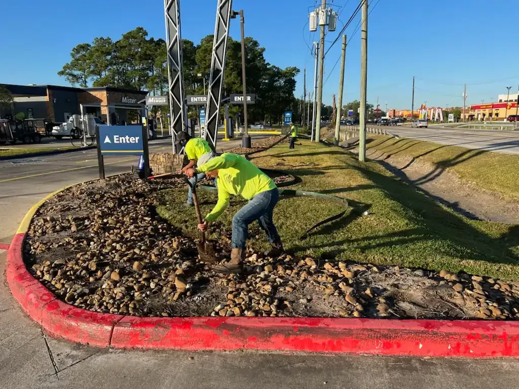 A man is digging in the dirt near a red curb.