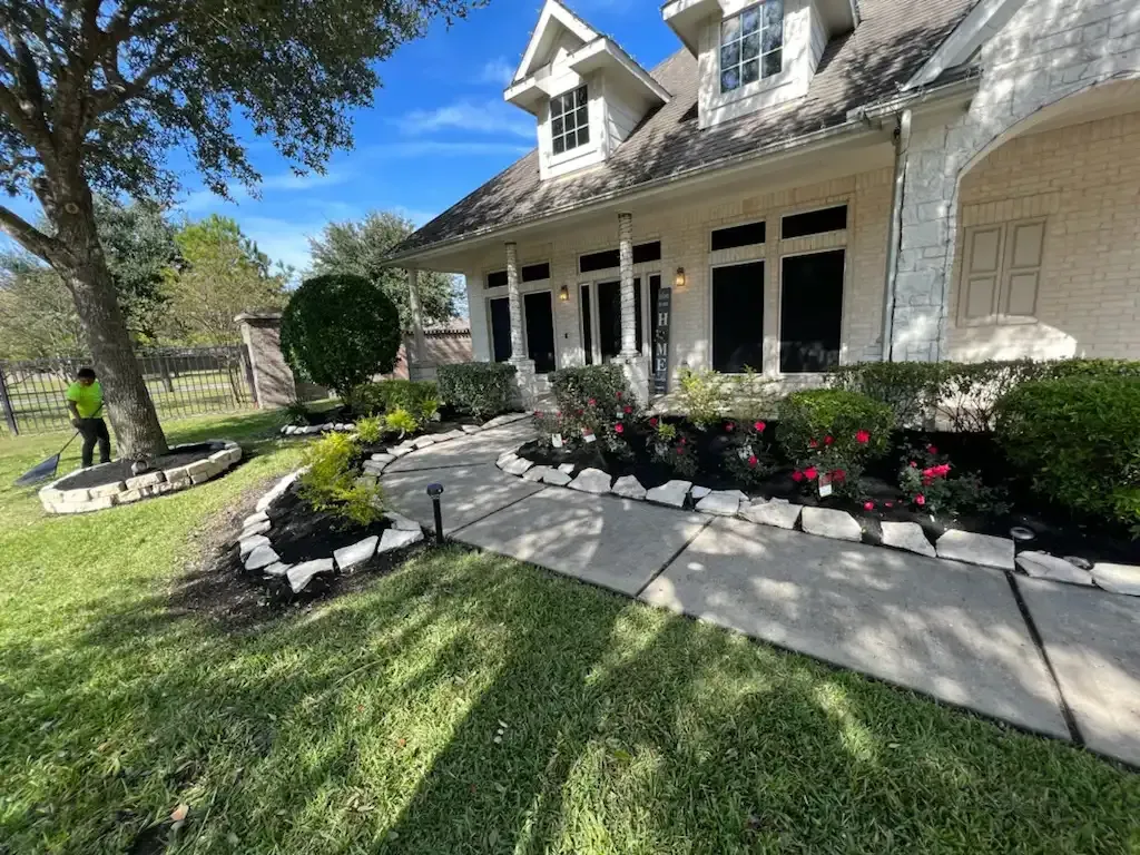 A man is standing in front of a large house with a walkway leading to it.