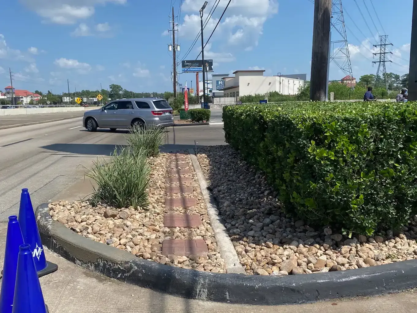 A car is parked on the side of the road next to a bush.