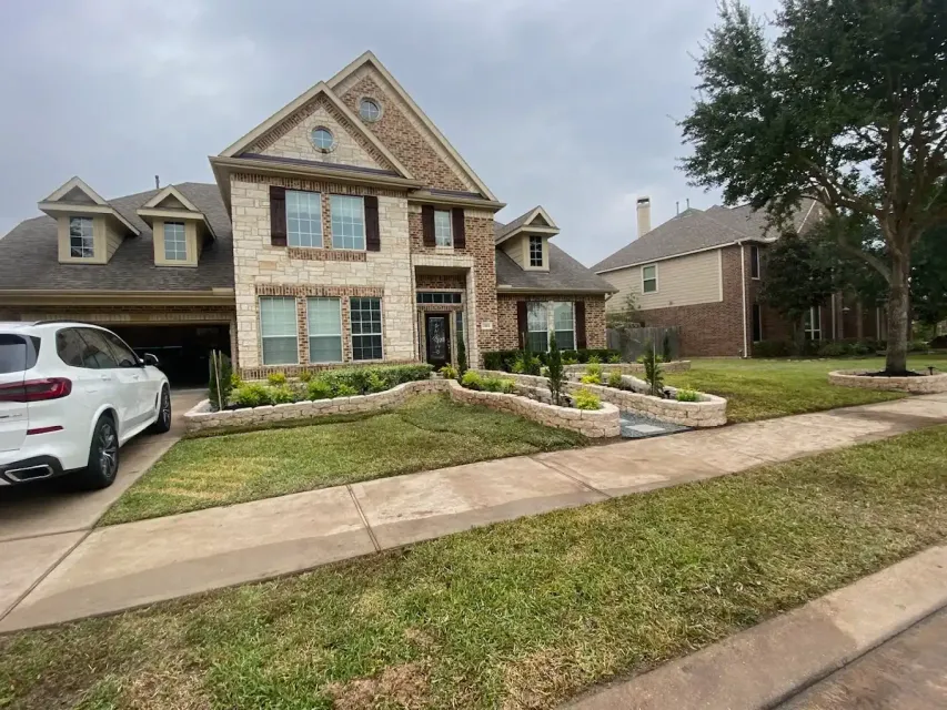 A white car is parked in front of a large house.