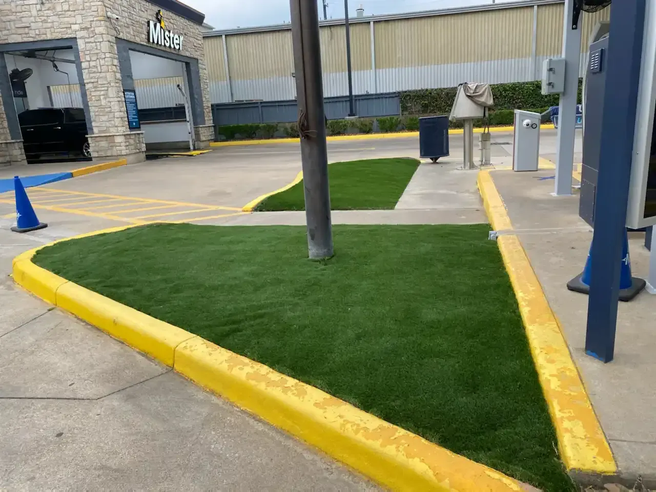 A grassy area with a yellow curb in front of a car wash.