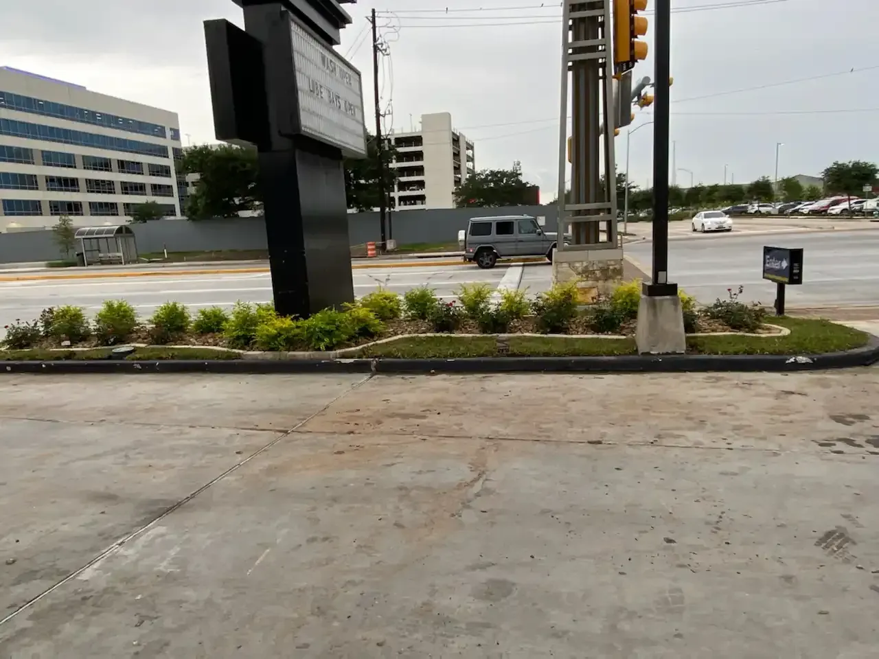 A gray van is parked on the side of the road next to a sign.