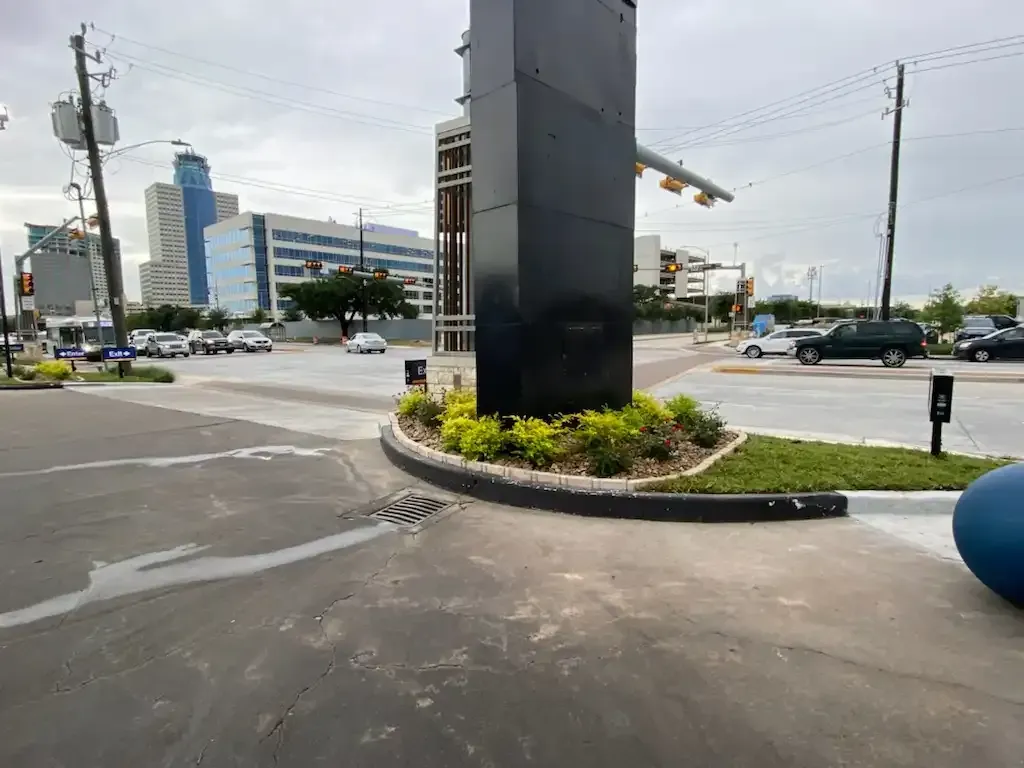 A busy intersection with a large black pillar in the middle of it.
