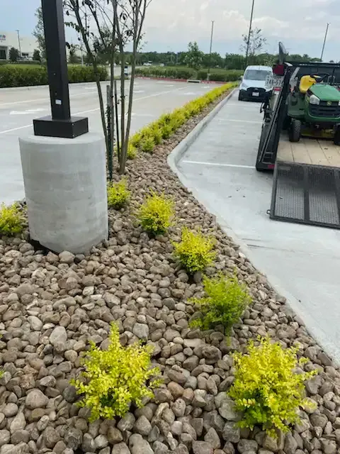 A green car is being towed by a flatbed truck in a parking lot.