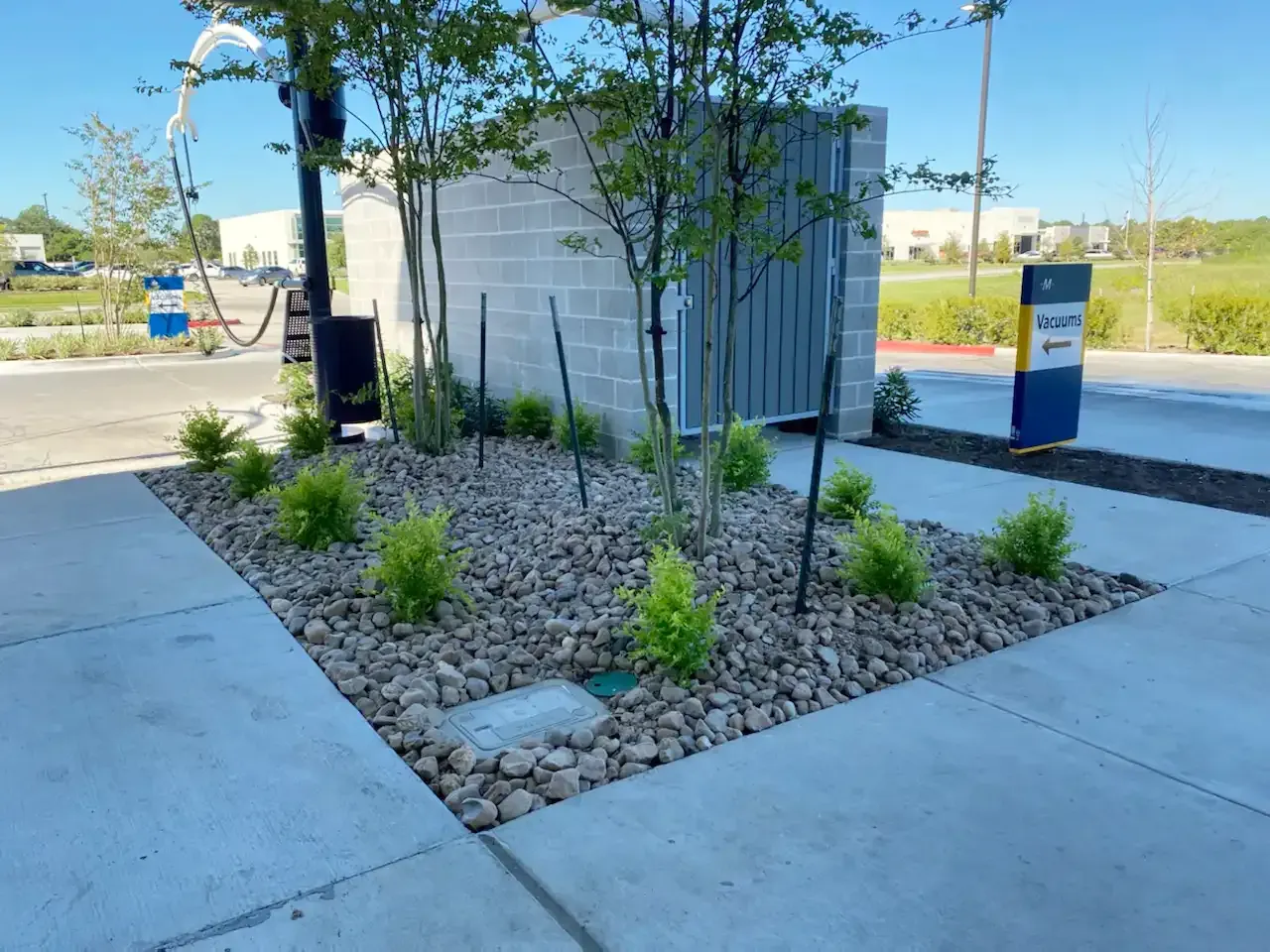 A concrete walkway with a planter filled with rocks and plants.