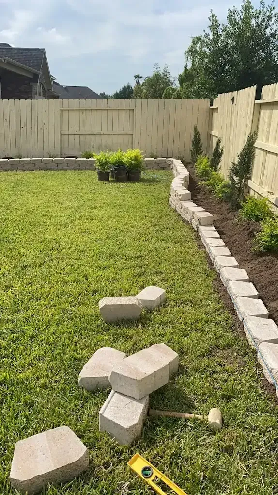 A fence is being built in a backyard with bricks and a level.