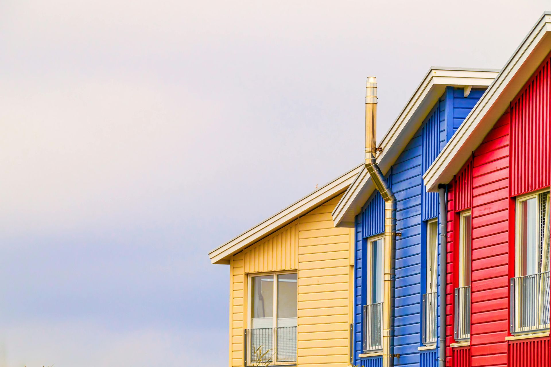 Colorful row of red, blue, and yellow houses with gabled roofs against a pastel sky