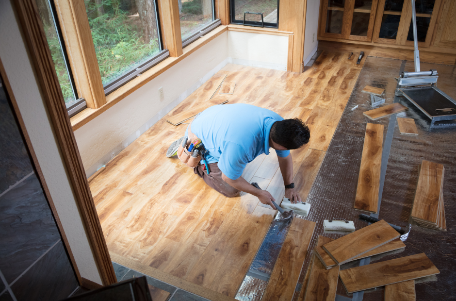 A picture of a man laying down wood floors in a house in Asheville, NC